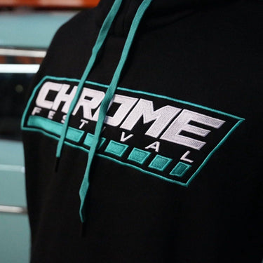 Black hoodie with 'Chrome Festival' logo worn by a person, with a blurred background.