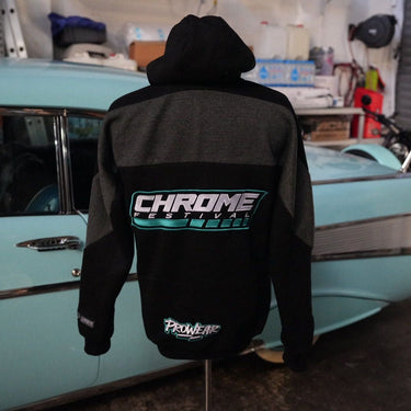 Person wearing a black hoodie with 'Chrome Industries' logo in front of a vintage boat.